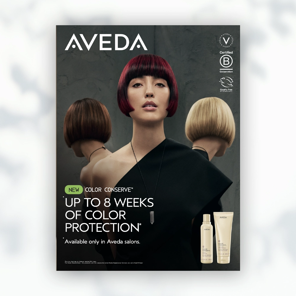'n Vrou met 'n donker bob-kapsel staan voor twee mannekyne met ligter bob-pruike. Aveda-handelsmerk en haarversorgingsprodukte word vertoon, wat kleurbeskerming bevorder. | Imaginal Marketing Store - An Aveda Partner